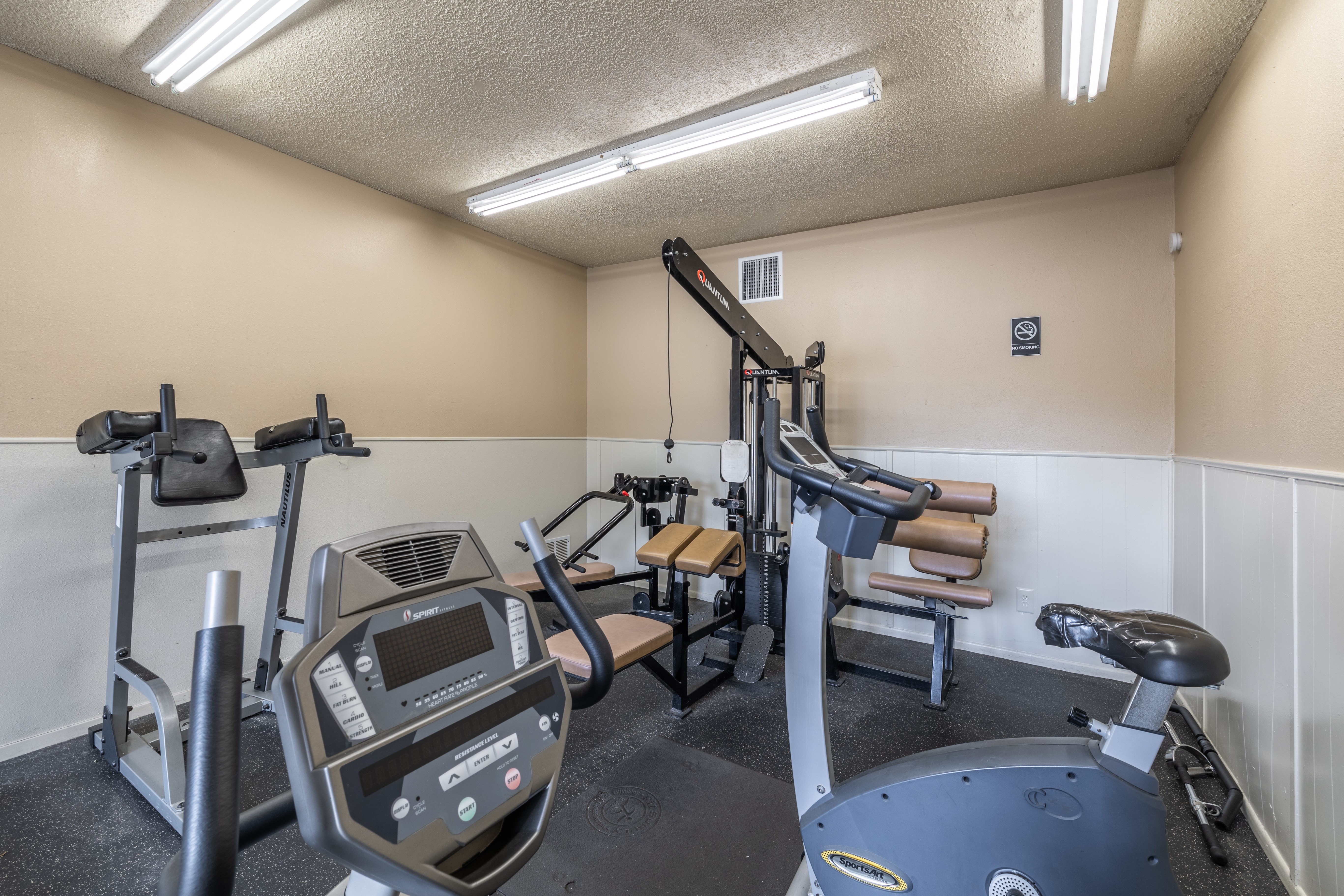 A gym with a treadmill, elliptical trainer, and a stationary bike.